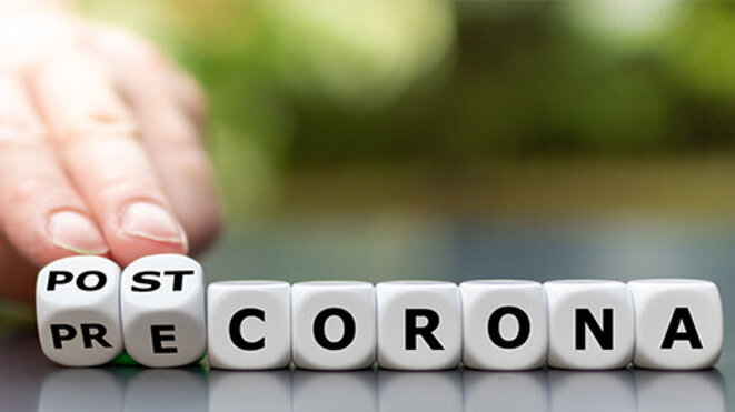 Hand turns dice and changes the expression "pre corona" to "post corona".