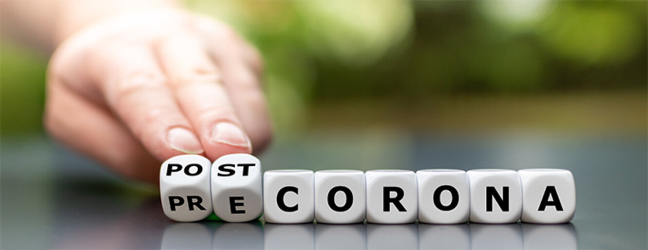 Hand turns dice and changes the expression "pre corona" to "post corona".