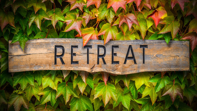 Wooden Retreat sign in front of wine leaves...