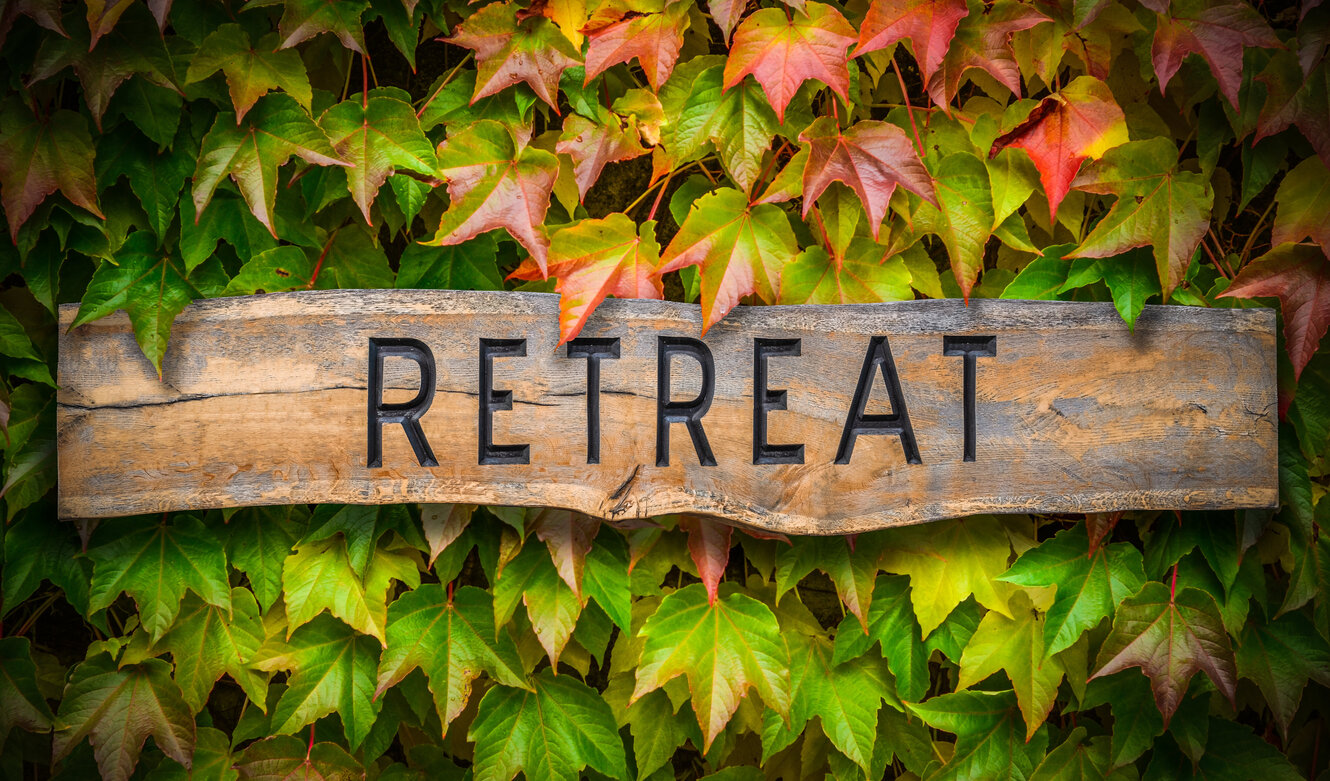 Wooden Retreat sign in front of wine leaves...