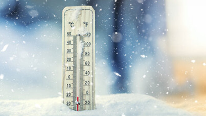 On the left - thermometer on snow shows low temperatures under zero, on the right - thermometer with high temperature plug on sand on sunny day