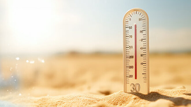 On the left - thermometer on snow shows low temperatures under zero, on the right - thermometer with high temperature plug on sand on sunny day