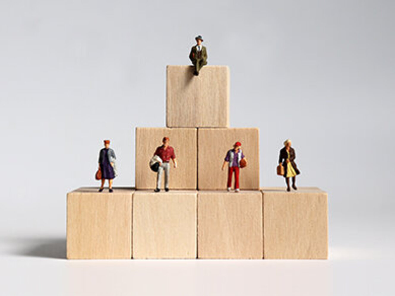 Wooden blocks and miniature people. Concept of layered social structure.