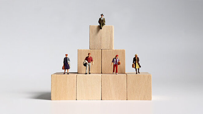 Wooden blocks and miniature people. Concept of layered social structure.
