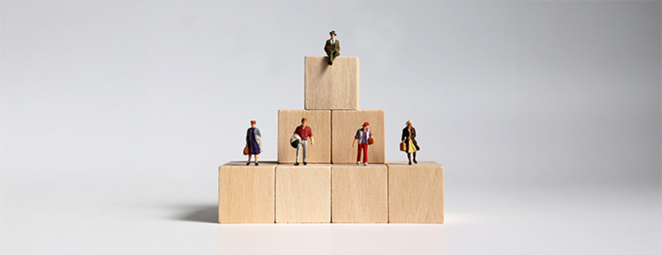 Wooden blocks and miniature people. Concept of layered social structure.