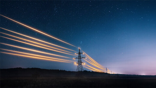 Electricity transmission towers with orange glowing wires the starry night sky. 