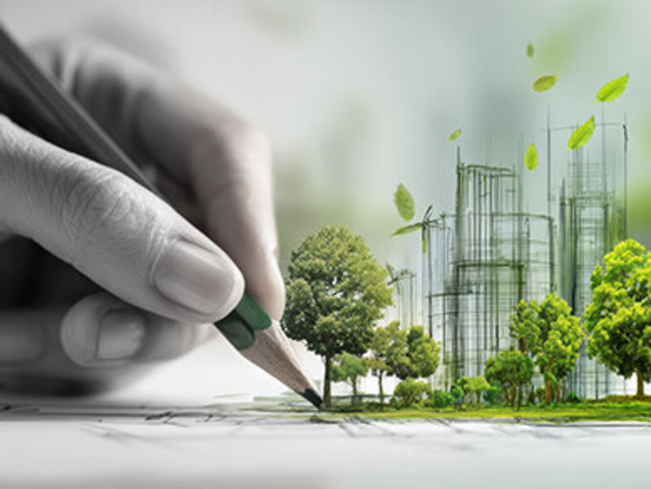 A hand drawing a sustainable urban development with green trees and wind turbines.