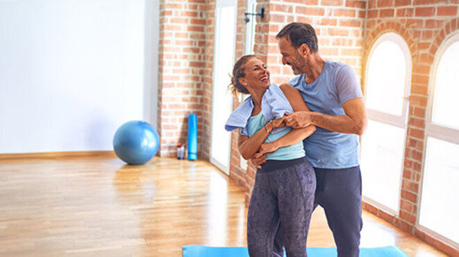 Middle age beautiful sporty couple smiling happy. Standing with smile on face hugging at gym