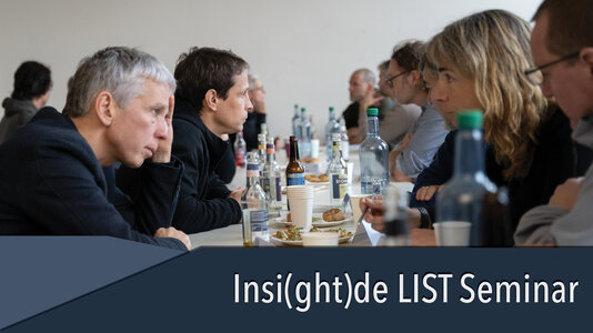Group of people sitting on a long table, immersed in discussion
