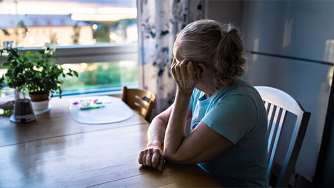 Elder person looking out the home window.